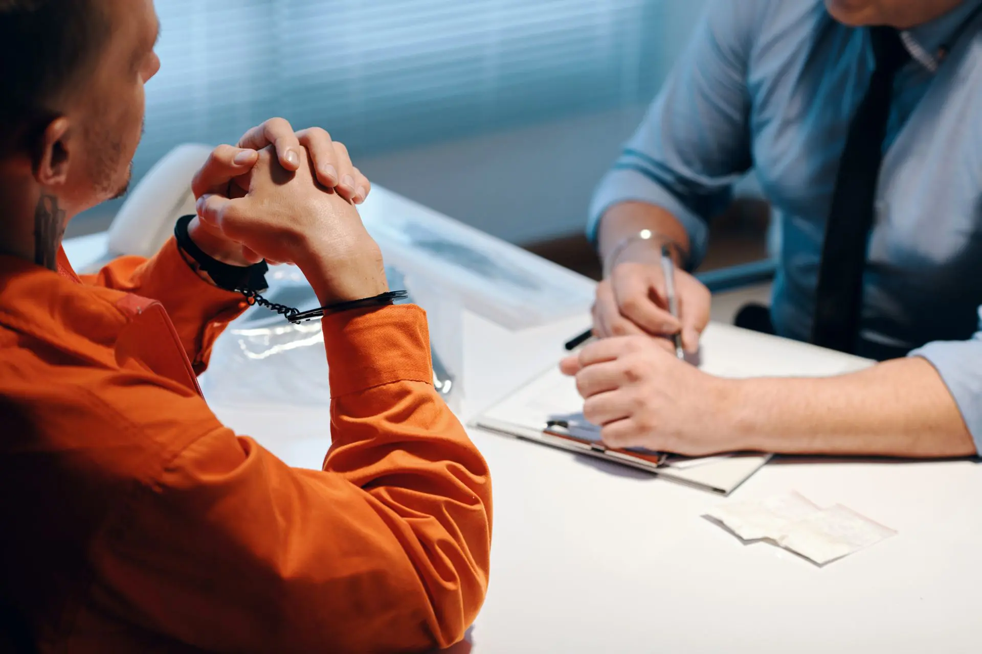 Two people sitting at a table with papers and pens.